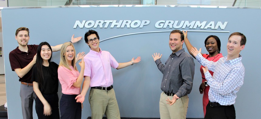 Northrop Grumman interns pose in front of a company sign.