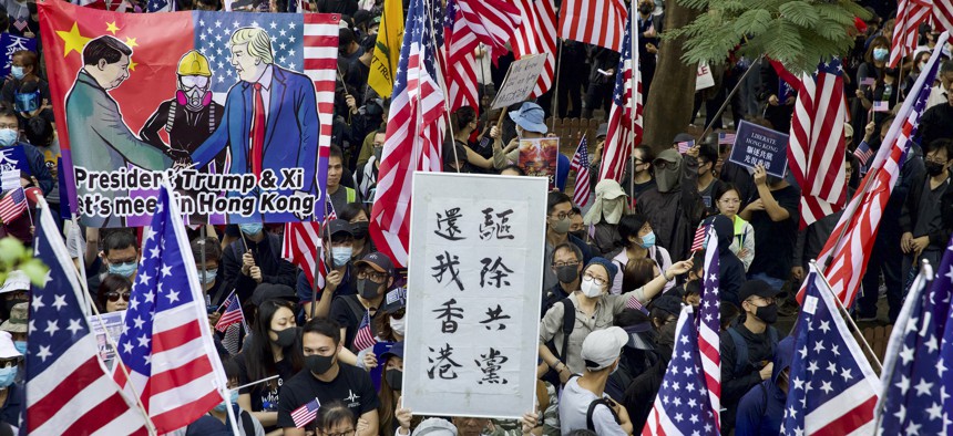 In this Dec. 1, 2019, file photo, protesters wave United States flags and a banner with the words "Chase away Communists and return my Hong Kong" during a rally march towards the U.S. consulate in Hong Kong. 