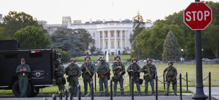 Law enforcement officers from Calvert County Maryland Sheriff's Office standing on the Ellipse, area just south of the White House in Washington, as they watch demonstrators protest the death of George Floyd, Sunday, May 31, 2020. 