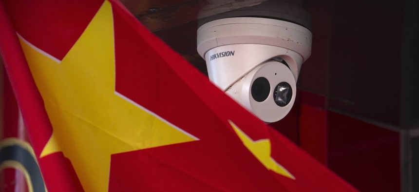 A Chinese flag hangs near a Hikvision security camera outside of a shop in Beijing, Tuesday, Oct. 8, 2019. 