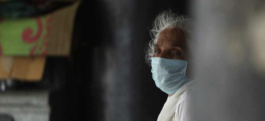 A woman wearing a face mask as a precaution against the coronavirus sits at a bus station in Jammu, India, Thursday, July 9, 2020. India has overtaken Russia to become the third worst-affected nation by the coronavirus pandemic. 