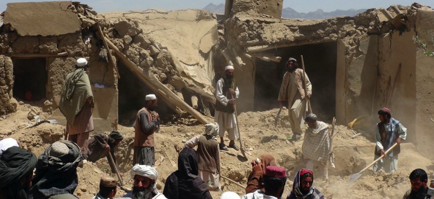 In this June 6, 2012, photo, Afghan villagers gather near a house destroyed in an apparent NATO raid in Logar province, south of Kabul. Afghanistan's president says the US has put the two countries' pact at risk with an airstrike that killed 18 civilians.