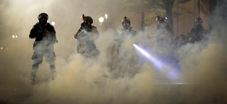 Federal officers are surrounded by smoke as they push back demonstrators during a Black Lives Matter protest at the Mark O. Hatfield United States Courthouse Wednesday, July 29, 2020, in Portland, Ore.