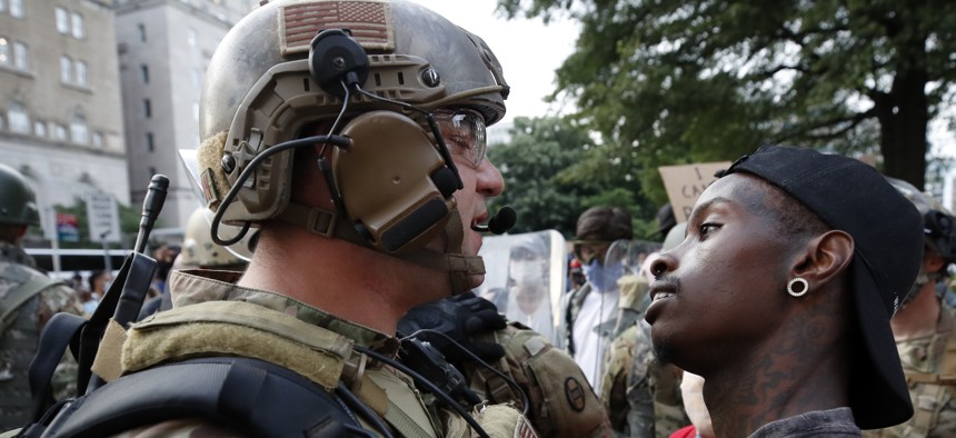 A demonstrator stares at a National Guard solider as protests continue over the death of George Floyd, Wednesday, June 3, 2020, near the White House in Washington.
