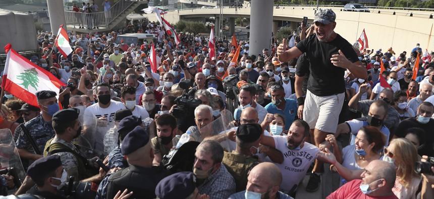 Supporters of Lebanese President Michel Aoun arguing with riot police as they try to take a main road that links to the presidential palace before the arrival of the anti-government protesters, in Baabda east of Beirut, Lebanon, Saturday, Sept. 12, 2020.