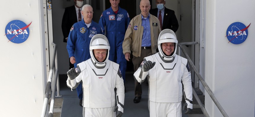 NASA astronauts Douglas Hurley, left, and Robert Behnken walk out of the Neil A. Armstrong Operations and Checkout Building on their way to Pad 39-A, at the Kennedy Space Center in Cape Canaveral, Fla.