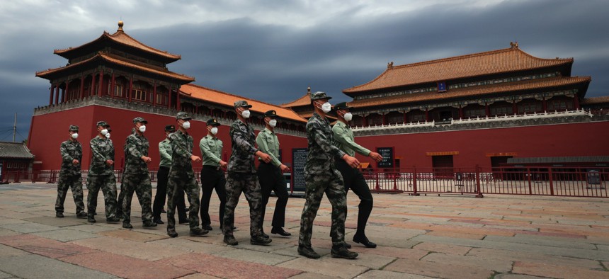 Chinese People's Liberation Army soldiers march past the closed Forbidden City in Beijing on May 25, 2020.