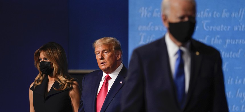First lady Melania Trump, left, and President Donald Trump, center, remain on stage as Democratic presidential candidate former Vice President Joe Biden, right, walk away at the conclusion of the second and final presidential debate Thursday.