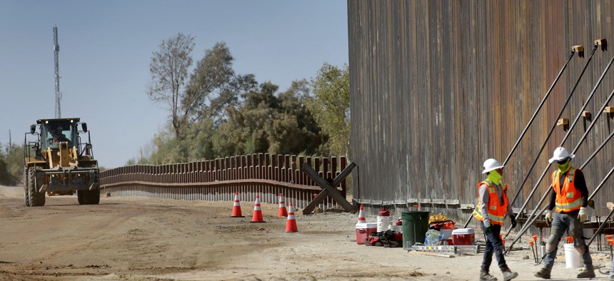 In this Sept. 10, 2019, file photo, government contractors erect a section of Pentagon-funded border wall along the Colorado River, in Yuma, Ariz. 