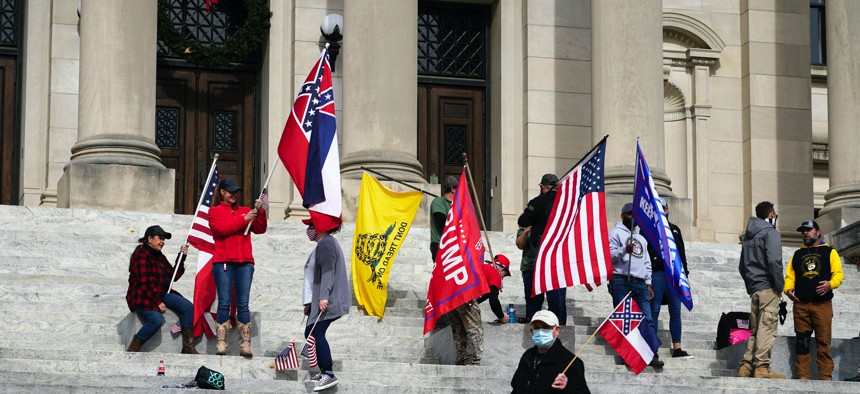 Protestors at the Mississippi state capitol wave the former state flag with its Confederate emblem, the Gadsden flag, and pro-Trump banners on Jan. 6, 2021.