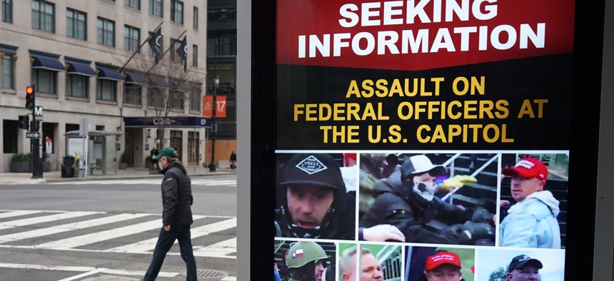 A monitor at a bus shelter near the White House shows images of people wanted in connection with the insurrection at the US Capitol in Washington, DC on January 14, 2021.