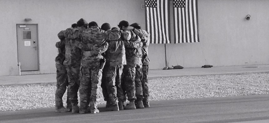 Soldiers of Special Forces, 10th Special Forces Group (Airborne) huddle together for strength as they memorialize two of their fallen brothers during a memorial held at Kunduz Airfield in Afghanistan on Nov. 7, 2016. 