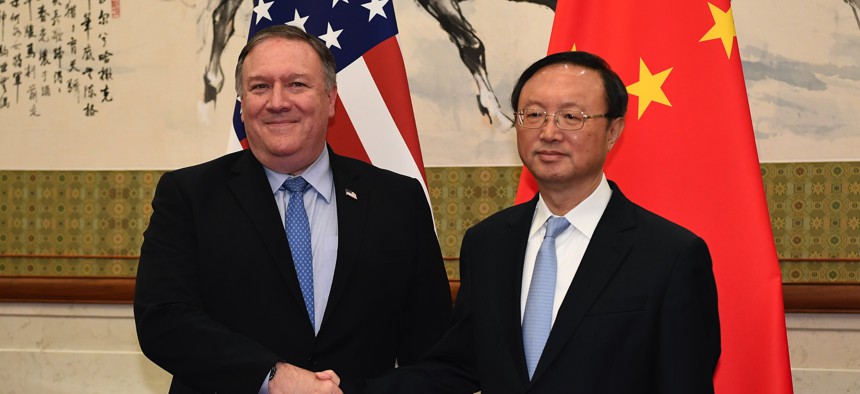 Happier times: Mike Pompeo, who as Secretary of State met with China's State Councillor Yang Jiechi in Beijing in 2018, has been banned from the country.