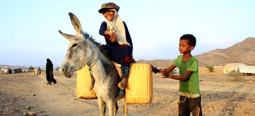 A girl rides a donkey carrying jerry cans filled with water from a cistern at a make-shift camp for displaced Yemenis in severe shortage of water, in the northern Hajjah province on March 24, 2020.