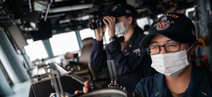 Ens. Jessica Cruz shoots a line of bearing on the bridge of the guided-missile destroyer USS Barry (DDG 62) as the ship conducts routine underway operations in the Taiwan Strait.
