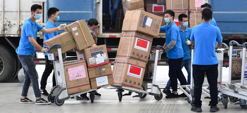 Workers carry boxes of medical supplies which will be donated to Zimbabwe at Huanghua International Airport on May 10, 2020 in Changsha, Hunan Province of China. 