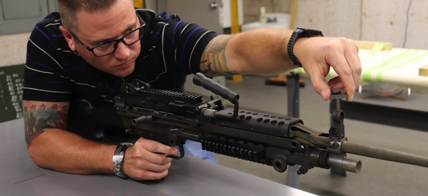 David Blaylock, Simulation & Test Range Division chief, uses a 3D-printed part to adjust an M240 machine gun.