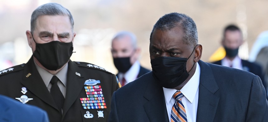 Chairman of the Joint Chiefs of Staff Gen. Mark Milley, left, looks on as Defense Secretary Lloyd Austin arrives at the Pentagon.