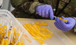 An airman assembles COVID-19 vaccine syringes.