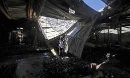 A Palestinian worker salvages items from a damaged factory in Gaza's industrial area, on May 25, 2021.