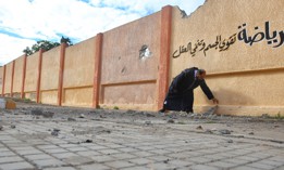 A school director in Tripoli, Libya, shows holes on the wall of a damaged school building that was targeted by airstrikes of Haftars' forces on January 10, 2020.
