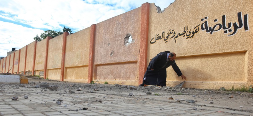 A school director in Tripoli, Libya, shows holes on the wall of a damaged school building that was targeted by airstrikes of Haftars' forces on January 10, 2020.