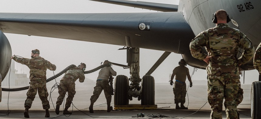 Airmen connect a fuel host to a U.S. Air Force KC-135 Stratotanker aircraft at Doha Air Base, Qatar, Jan. 21, 2021.