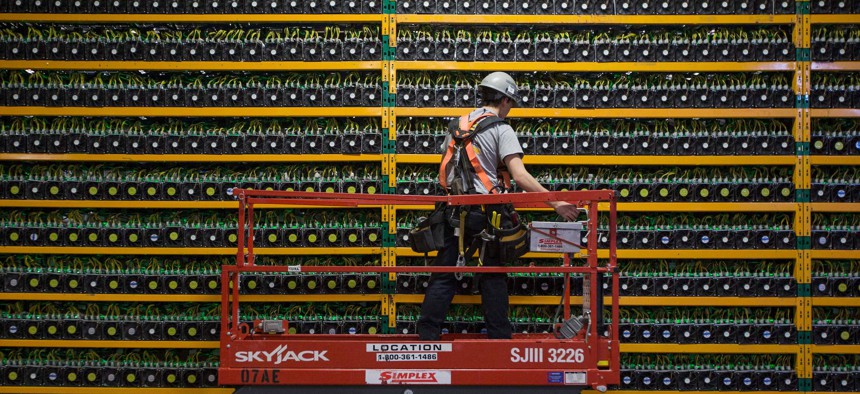 A technician inspects the backside of bitcoin mining at Bitfarms in Saint Hyacinthe, Quebec on March 19, 2018.