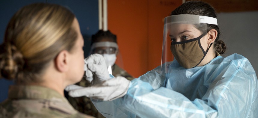 Army Spc. Elizabeth Porter, a field medic, swabs a fellow soldier’s nose for a COVID-19 test at Farke Airfield, Albania, May 16, 2021.