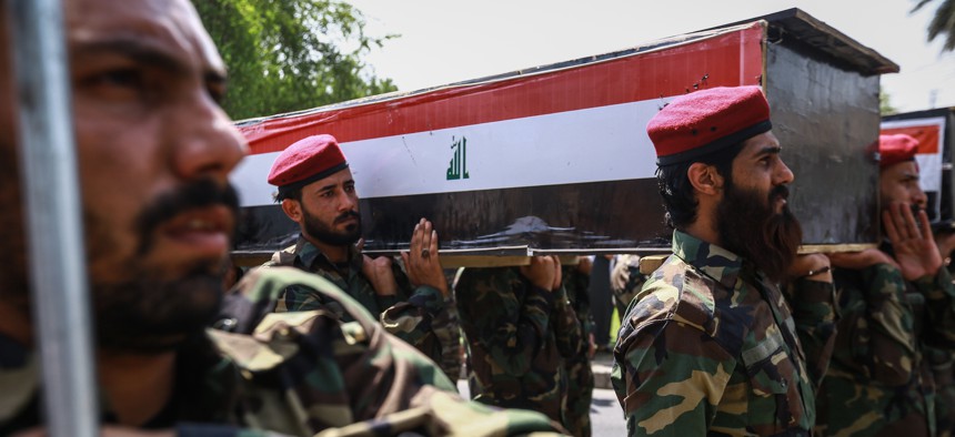 Members of the Popular Mobilization Forces, also known as the Hashd al-Shaabi, carry the body of a colleague, killed along with six others during US airstrikes on the Iraqi-Syrian border city of Al-Qaim on June 29, 2021.