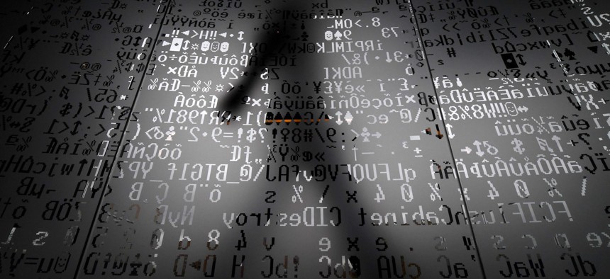 A picture taken on October 17, 2016 shows an employee walking behind a glass wall with machine coding symbols at the headquarters of Internet security giant Kaspersky in Moscow.