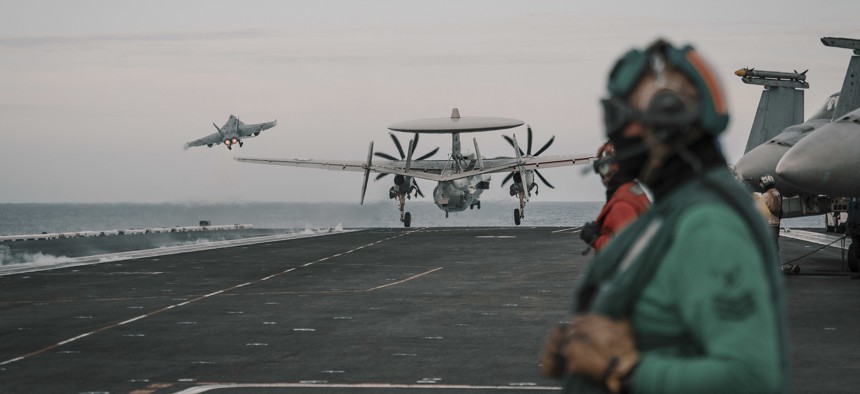 An F/A-18E Super Hornet and an E-2C Hawkeye launch from the flight deck of the aircraft carrier USS Theodore Roosevelt.