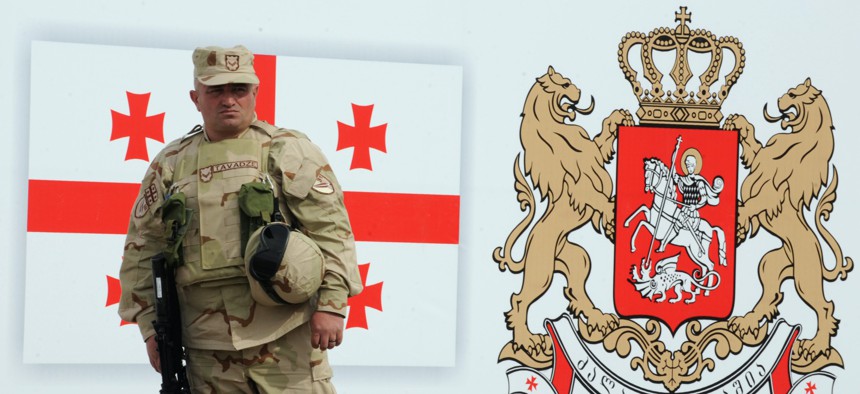 A Georgian soldier stands in front of a drawing of a Georgian flag and national emblem during a farewell ceremony before a deployment to Helmand province, Afghanistan, in 2010. 