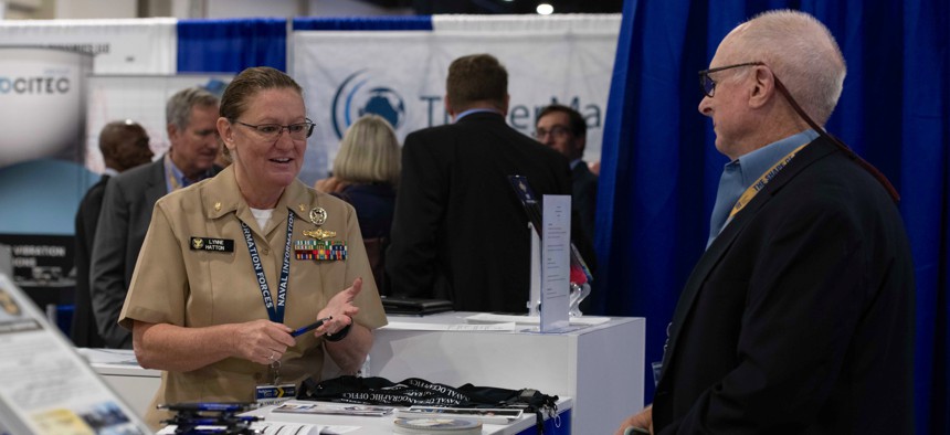 Lt. Cmdr. Lynne Hatton speaks with an attendee at the Naval Information Warfare booth during the Sea Air Space 2021 exposition.
