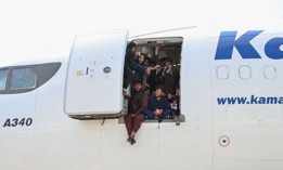 Afghan people climb up on a plane and sit by the door as they wait at the Kabul airport in Afghanistan, August 16, 2021.