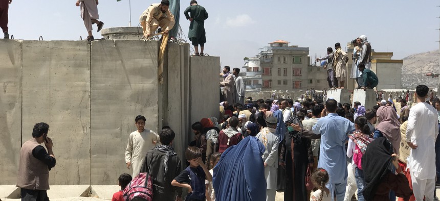 People struggle to cross the boundary wall of Hamid Karzai International Airport to flee the country after the Taliban over run of Kabul, Afghanistan, August 16, 2021.