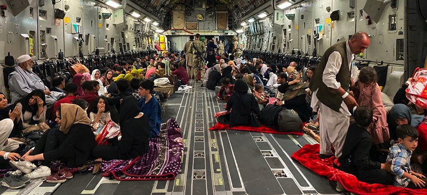 Afghan people sit inside a U S military aircraft to leave Afghanistan, at the military airport in Kabul on August 19, 2021 after Taliban's military takeover of Afghanistan.