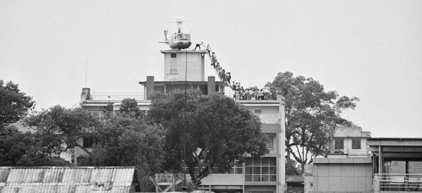 A CIA employee helps Vietnamese evacuees onto an Air America helicopter from the top of 22 Gia Long Street, a half mile from the U.S. Embassy.