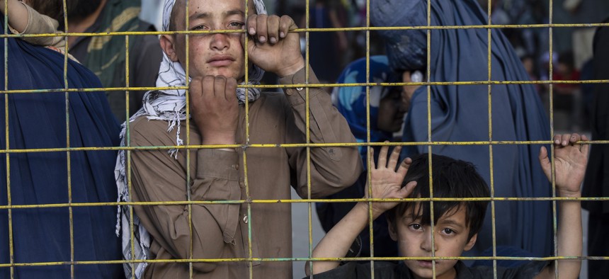 Displaced Afghans look through a fence at a makeshift IDP camp on August 12, 2021 in Kabul, Afghanistan.