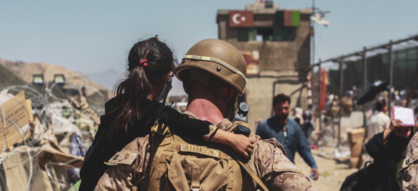 A Marine assigned to Special Purpose Marine Air Ground Task Force-Crisis Response- Central Command carries a child to be processed during an evacuation at Hamid Karzai International Airport, Kabul, Afghanistan, Aug. 25. 