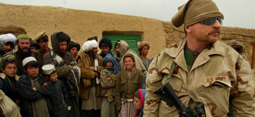 A U.S. Army Special Forces soldier is surrounded by a curious crowd of Afghan onlookers in a remote village in the mountains of western Afghanistan in 2002. 