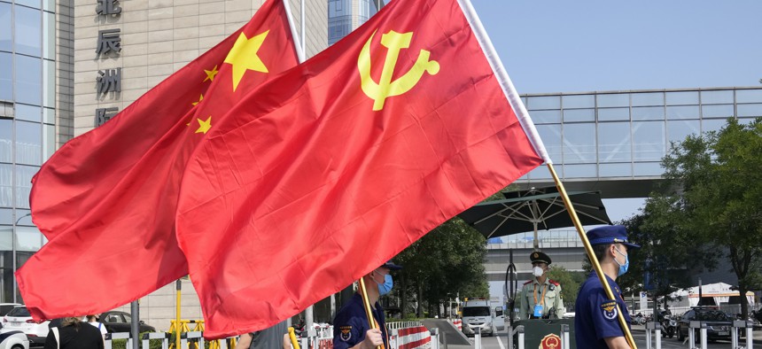 Security personnel holding the Communist Party and Chinese national flags prepare to enter the venue for the China International Fair for Trade in Services in Beijing, China, Sept. 2, 2021. 