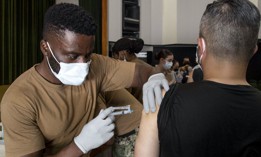 Navy Seaman Valentine Anebere, a hospital corpsman assigned to U.S. Naval Hospital Yokosuka Branch Health Clinic Sasebo, administers doses of the Moderna COVID-19 vaccine to an employee at Commander Fleet Activities Sasebo, Japan, July 28, 2021.