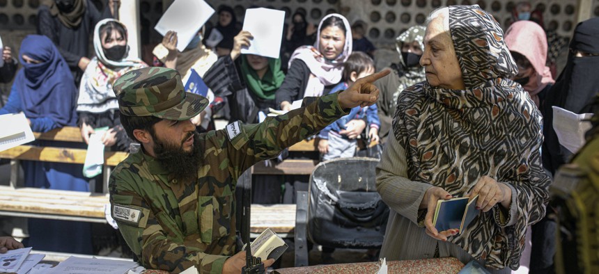 A Taliban fighter talks with an elderly woman at the government passport office which re-opened after the Taliban announced they would be issuing a backlog of applications approved by the previous administration in Kabul, Afghanistan, Oct. 17, 2021.