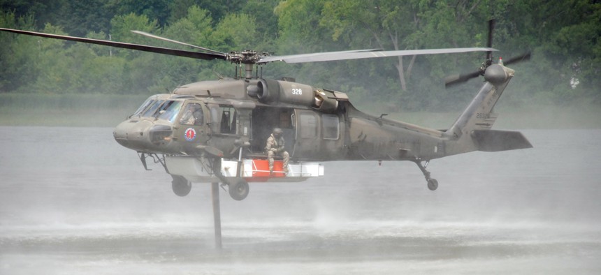 A UH-60 Blackhawk helicopter of the New York Army National Guard's 3rd Battalion 142nd Aviation in Latham hovers above the Mohawk River as the crew fills the Firehawk firefighting system attached to the underside of the helicopter.