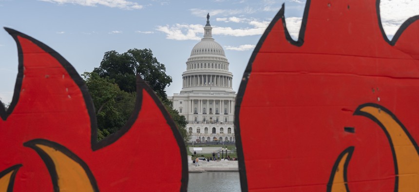 In this Oct. 15, 2021, photo, the U.S. Capitol is seen between cardboard cutouts of flames during a climate change protest near the U.S. Capitol in Washington. 