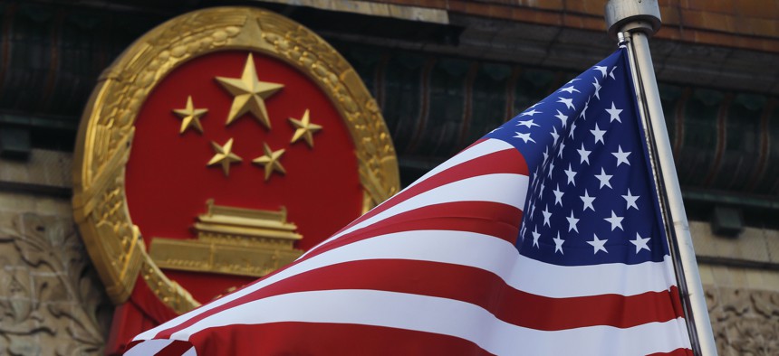 In this Nov. 9, 2017, file photo, an American flag is flown next to the Chinese national emblem during a welcome ceremony for visiting U.S. officials.
