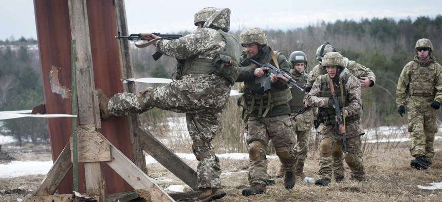 A Ukrainian combat training center engineer kicks in a door after using a breaching charge while training with Canadian and U.S. Army engineers near Yavoriv, Ukraine, on Feb. 23, 2017.