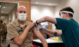 Cmdr. Jeremiah Anderson, left, receives the first COVID-19 vaccine dose administered during a vaccination event held onboard Washington Navy Yard in April 2021.