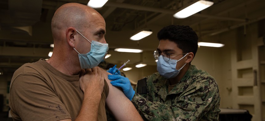 Hospitalman Christopher Ramirez, right, from Kimberly, Idaho, assigned to the medical department of the aircraft carrier pre-commissioning unit John F. Kennedy (CVN 79), administers a COVID-19 vaccine to Lt. Cmdr. George Stegeman, John F. Kennedy’s psychological officer, during a joint vaccination evolution aboard USS Gerald R. Ford (CVN 78), Sept. 30, 2021.
